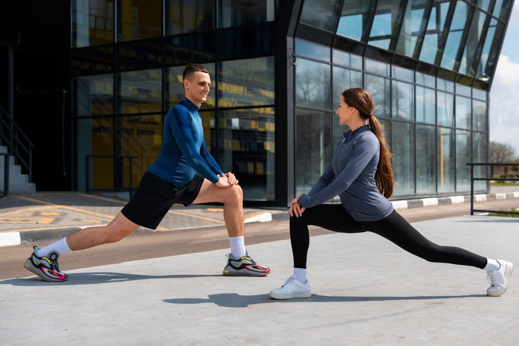 Two people stretching outdoors in front of a modern building.